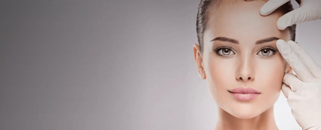 A woman prepares for a Botox treatment with a professional gently holding her forehead to administer the injection.
