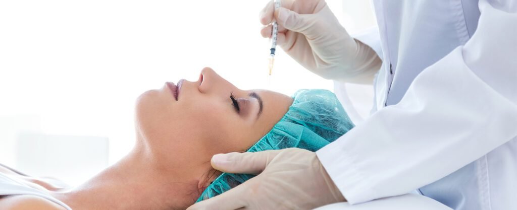 A woman receiving a cosmetic facial injection while lying down in a clinical setting.