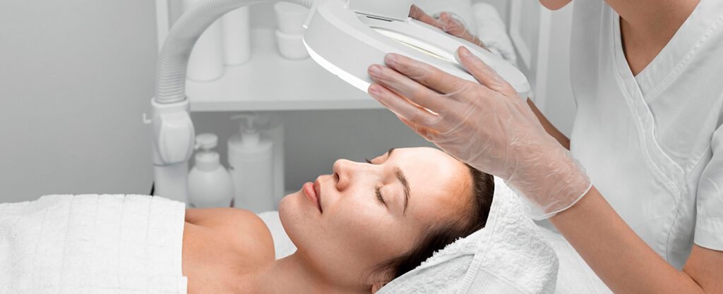 Woman receiving a facial treatment under a magnifying light.