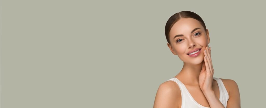 Woman smiling and touching her face with glowing skin.