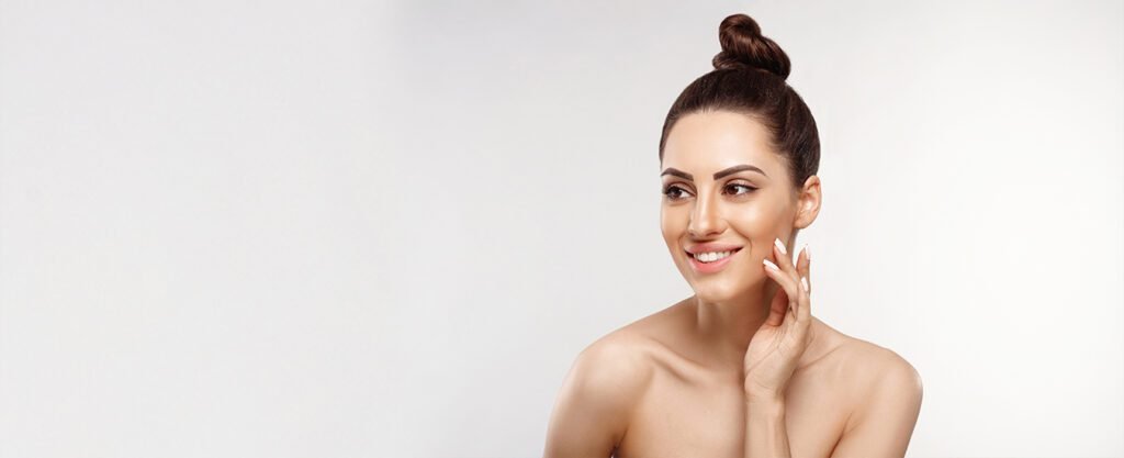 Woman smiling and touching her face with clear skin.