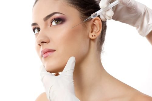 Cosmetic injection being administered near the temple area.