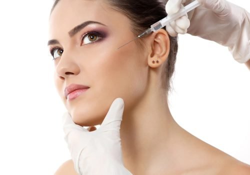 Cosmetic injection being administered near the temple area.