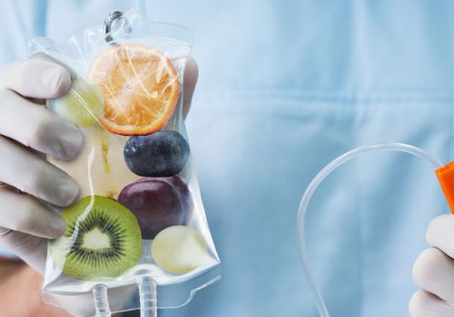 IV vitamin therapy bag filled with fruit imagery held by a medical professional.