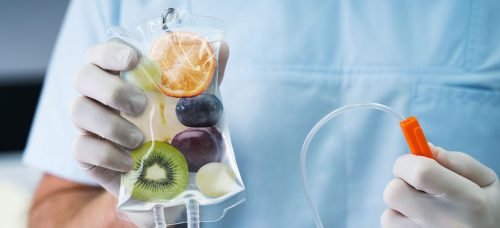 IV vitamin therapy bag filled with fruit imagery held by a medical professional.