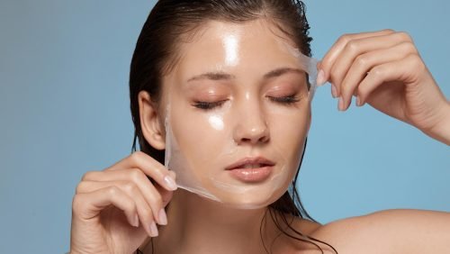 Woman peeling off a transparent facial mask from her face.