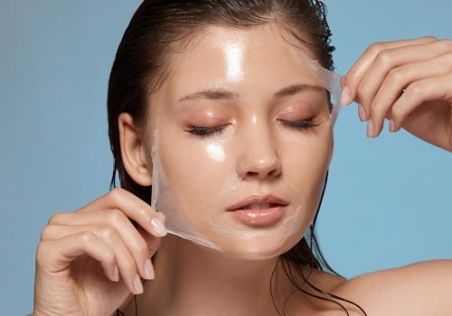 Woman peeling off a transparent facial mask from her face.