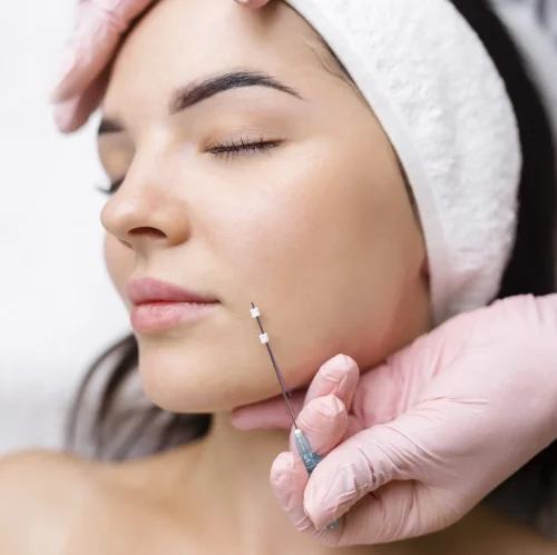 Cosmetic facial injection being performed along the jawline.